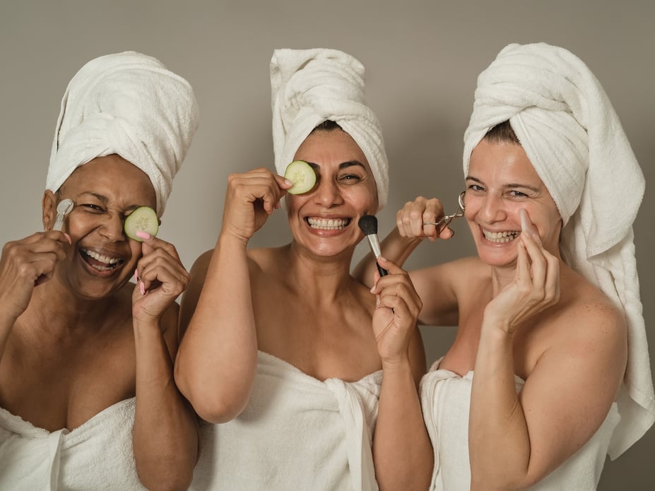 Women in Towels Holding Cucumber Slices and Cosmetic Brushes